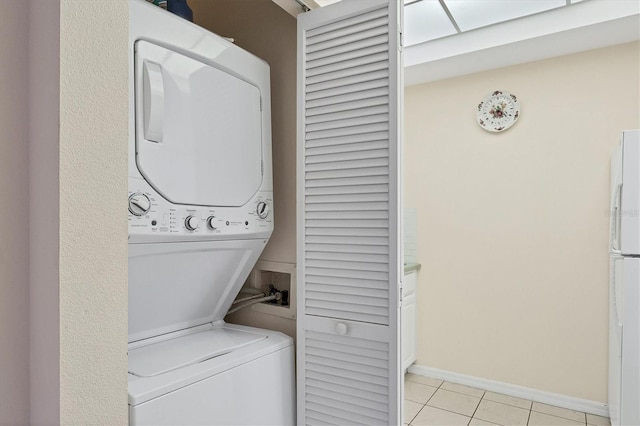 laundry area featuring light tile floors and stacked washer and dryer