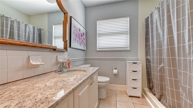 bathroom featuring backsplash, toilet, tile floors, and vanity with extensive cabinet space