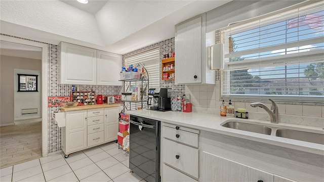 kitchen with backsplash, light hardwood / wood-style floors, black dishwasher, and white cabinetry