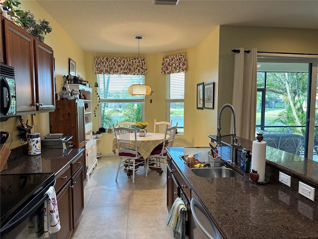 kitchen featuring plenty of natural light, sink, light tile floors, and decorative light fixtures