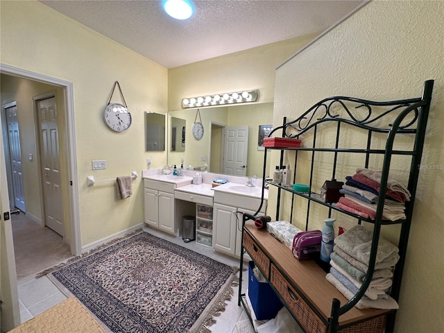 bathroom with dual sinks, vanity with extensive cabinet space, tile floors, and a textured ceiling