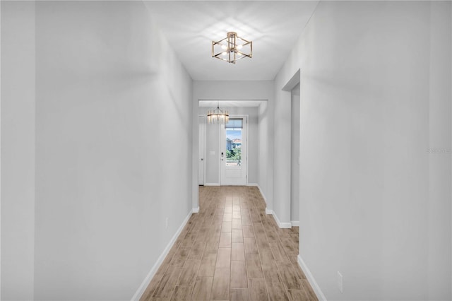 hallway featuring light hardwood / wood-style floors and a notable chandelier