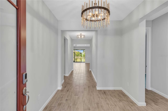 corridor featuring light hardwood / wood-style flooring and a notable chandelier