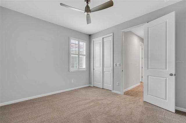 unfurnished bedroom featuring ceiling fan, a closet, and light carpet