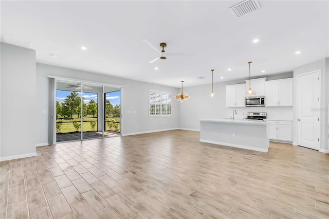 unfurnished living room featuring sink and ceiling fan with notable chandelier