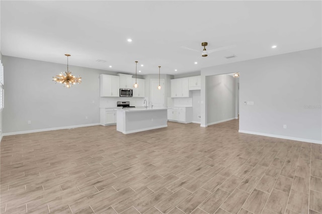 unfurnished living room featuring sink and ceiling fan with notable chandelier