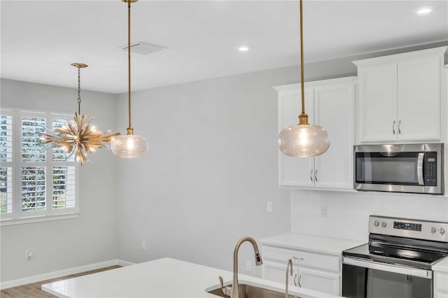 kitchen with appliances with stainless steel finishes, tasteful backsplash, white cabinetry, and pendant lighting