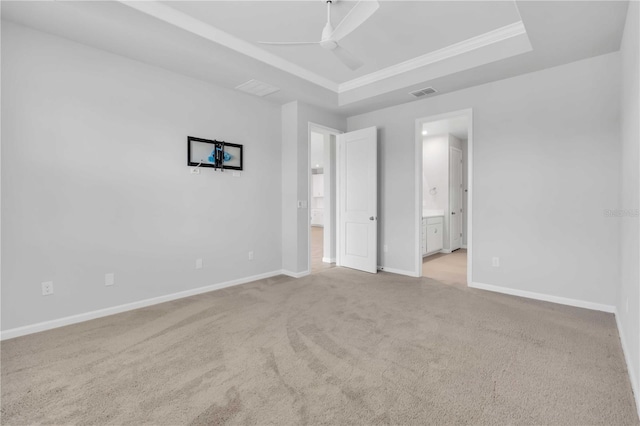 carpeted spare room with ceiling fan, ornamental molding, and a tray ceiling