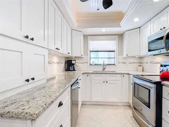 kitchen featuring tasteful backsplash, stainless steel appliances, white cabinets, and a tray ceiling