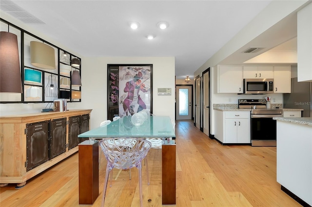 kitchen with white cabinetry, appliances with stainless steel finishes, and light hardwood / wood-style floors