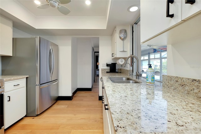 kitchen with white cabinetry, ceiling fan, a tray ceiling, and sink