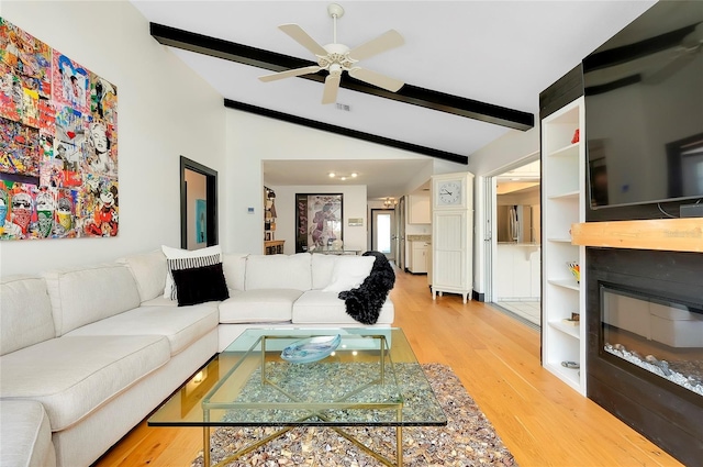 living room with ceiling fan, light hardwood / wood-style floors, lofted ceiling with beams, and built in features