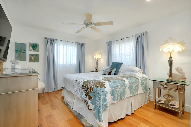 bedroom with ceiling fan, multiple windows, and light wood-type flooring