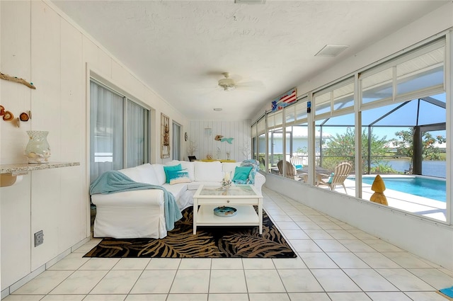 sunroom / solarium featuring ceiling fan and a water view