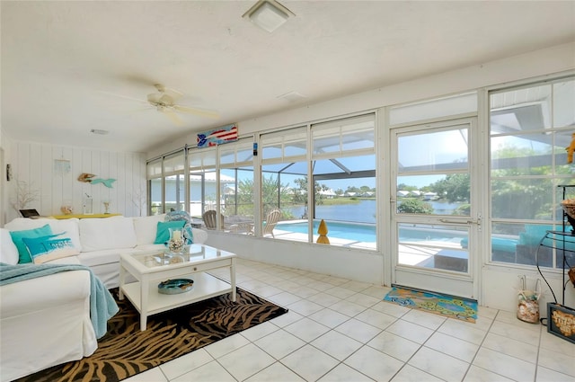 sunroom / solarium featuring ceiling fan and a water view