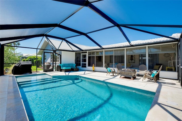 view of pool featuring a grill, a patio area, glass enclosure, and an outdoor living space with a fire pit