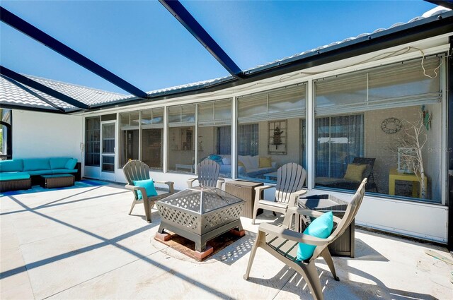 view of patio / terrace featuring an outdoor living space with a fire pit and a sunroom