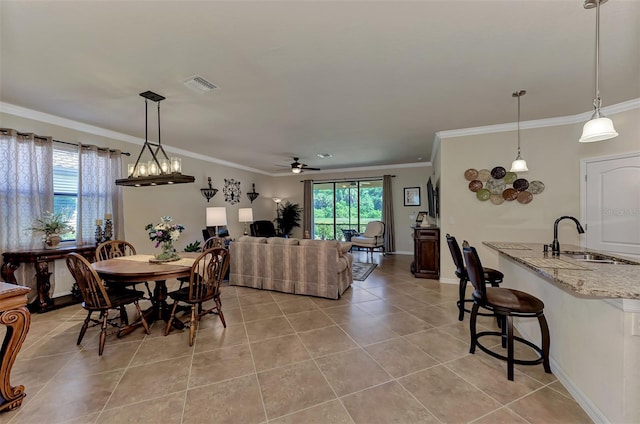 dining space with ceiling fan with notable chandelier, crown molding, tile flooring, and sink