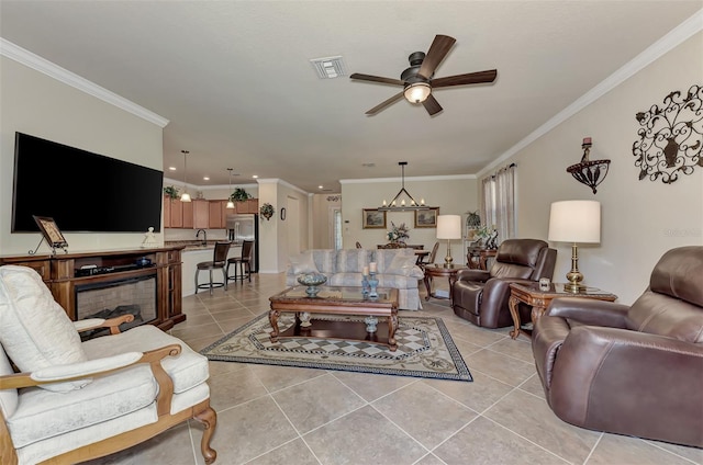 tiled living room featuring ornamental molding, sink, and ceiling fan with notable chandelier