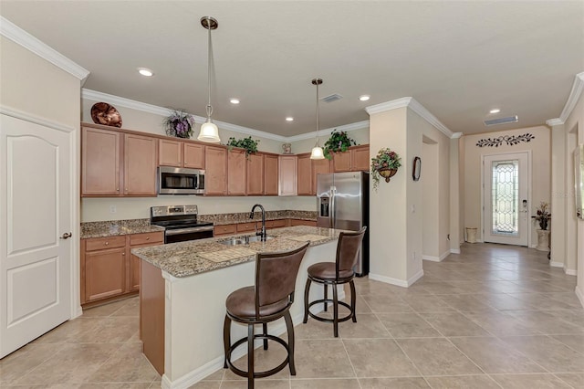 kitchen with a breakfast bar area, hanging light fixtures, stainless steel appliances, an island with sink, and light stone countertops