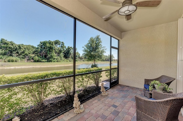 sunroom / solarium featuring ceiling fan and a water view