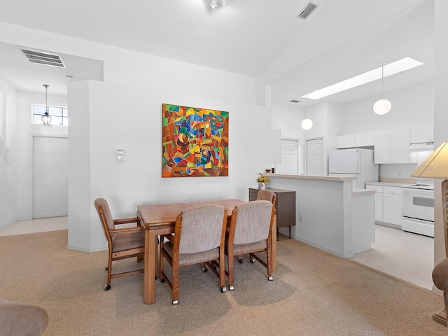 dining space with high vaulted ceiling and light carpet