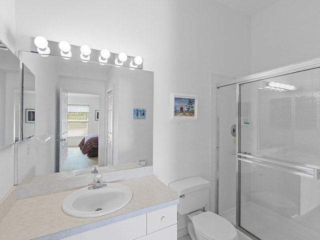 bathroom featuring vanity, a shower with shower door, and toilet