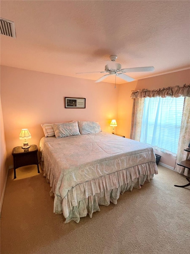 bedroom featuring carpet flooring, ceiling fan, and a textured ceiling