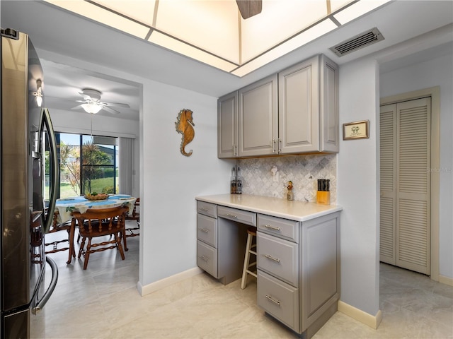 kitchen with ceiling fan, backsplash, gray cabinets, and stainless steel refrigerator