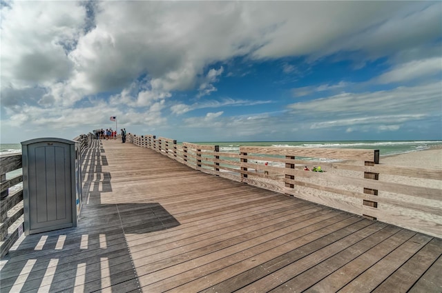 view of dock featuring a beach view and a water view