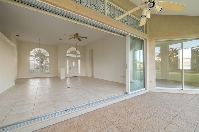 unfurnished room featuring ceiling fan, plenty of natural light, and a towering ceiling