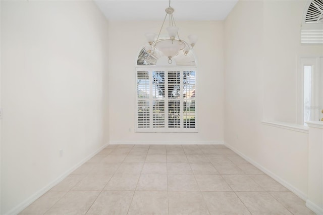 tiled empty room with an inviting chandelier