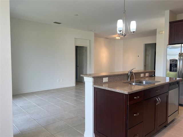 kitchen with light stone countertops, hanging light fixtures, light tile flooring, dishwasher, and sink