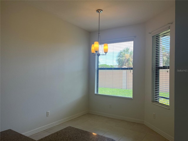 empty room featuring a healthy amount of sunlight, tile floors, and an inviting chandelier