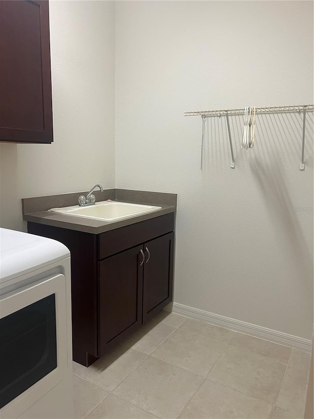 clothes washing area with cabinets, sink, washer / dryer, and light tile floors