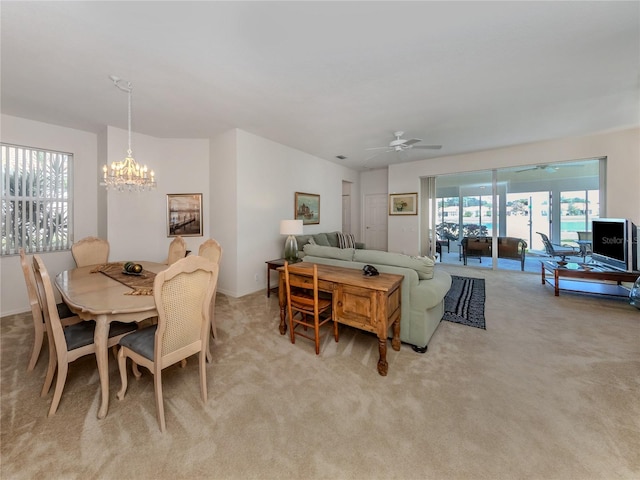 dining space with carpet flooring and ceiling fan with notable chandelier