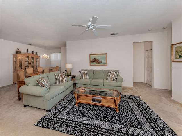 carpeted living room featuring ceiling fan with notable chandelier