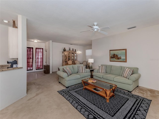 living room with light carpet, french doors, and ceiling fan with notable chandelier