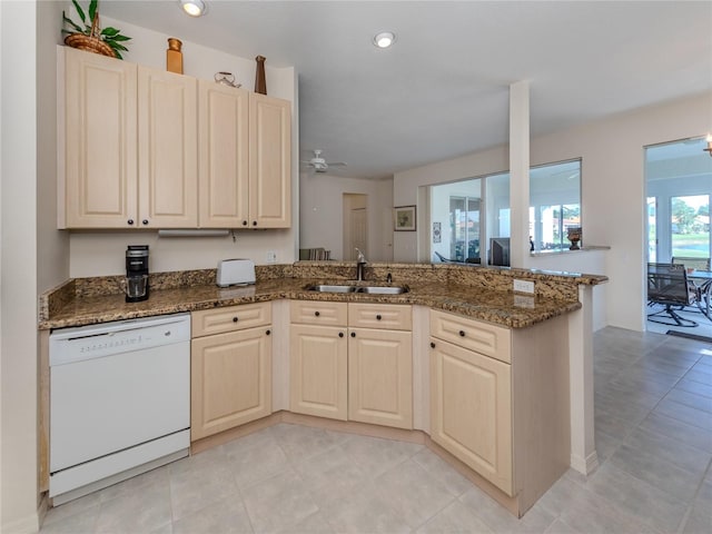 kitchen with kitchen peninsula, white dishwasher, light tile floors, sink, and dark stone counters