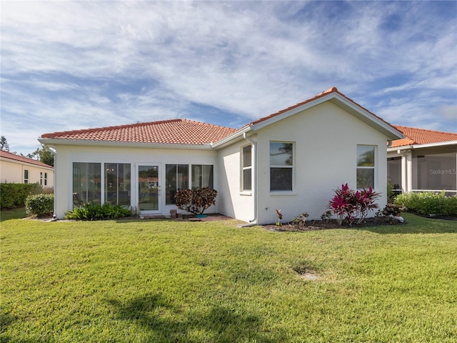 back of property featuring a lawn and a sunroom