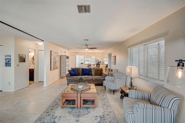 living room with ceiling fan, a textured ceiling, and light tile patterned flooring