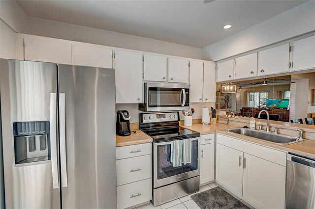 kitchen featuring stainless steel appliances, white cabinetry, sink, and light tile patterned flooring