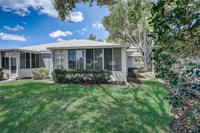 rear view of property featuring a yard and a sunroom