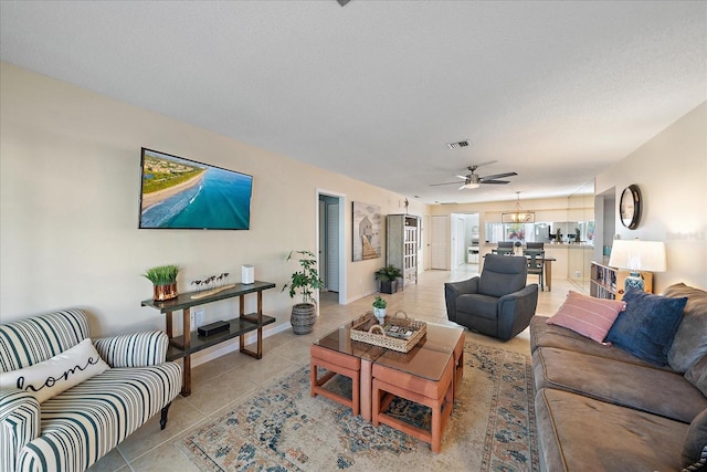 living room featuring light tile patterned flooring, ceiling fan, and a textured ceiling