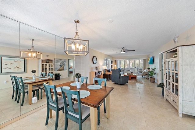 tiled dining room featuring ceiling fan with notable chandelier and a textured ceiling