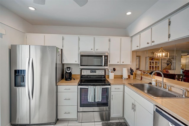 kitchen featuring stainless steel appliances, light tile patterned flooring, sink, and white cabinets