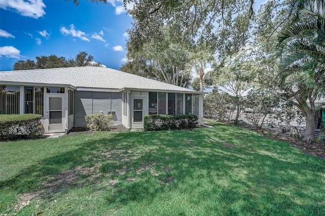 back of property with a sunroom and a lawn