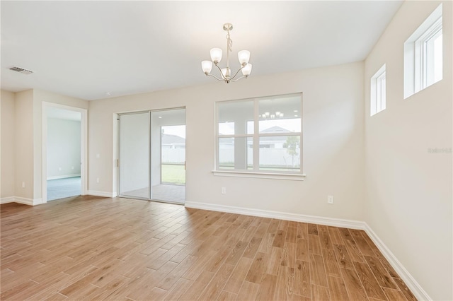 spare room featuring light hardwood / wood-style flooring and a notable chandelier