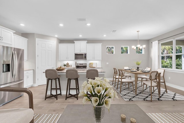 kitchen featuring decorative light fixtures, white cabinetry, stainless steel appliances, and a chandelier