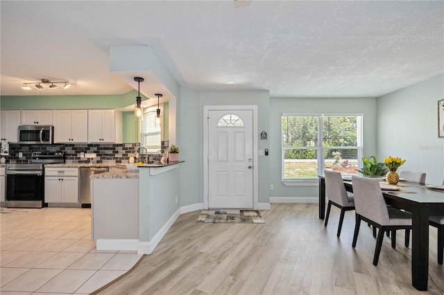 kitchen with a wealth of natural light, tasteful backsplash, appliances with stainless steel finishes, and white cabinetry